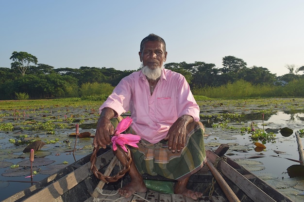 The bearded man leaves the boat oar and is busy making garlands of water lilies.