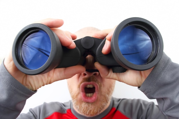 Bearded man looking through binoculars on white background