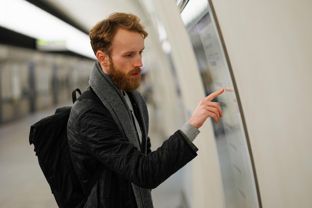 Bearded man looks at a subway train map