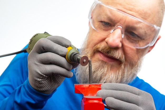 Bearded man mechanic processes metal with an engraving drill Locksmith industry