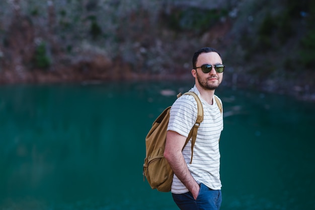 ひげを生やした男性モデルは、緑の水湖と一緒にポーズします。