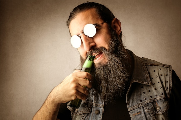 Bearded man opening a beer with his teeth