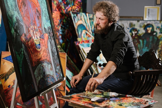 a bearded man painter or artist painting his masterpiece in his workshop