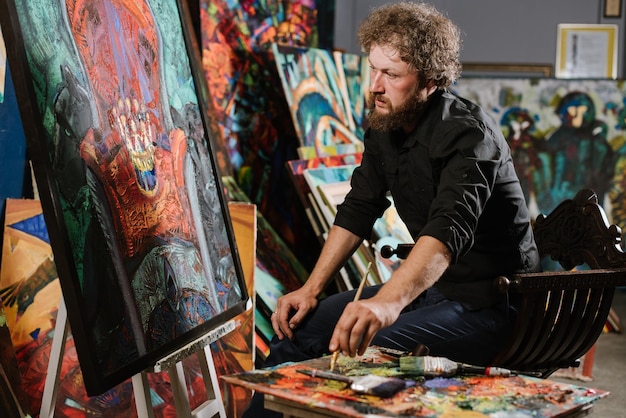 A bearded man painter or artist painting his masterpiece in his workshop