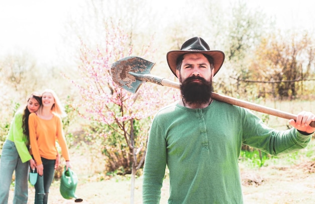 Bearded man planting plants in spring garden teamwork and friends togetherness concept