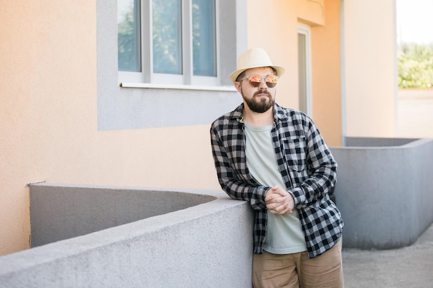 Ritratto di uomo barbuto in abiti estivi e cappello in piedi sopra la città di strada e il concetto di viaggio copia spazio e spazio vuoto per la pubblicità