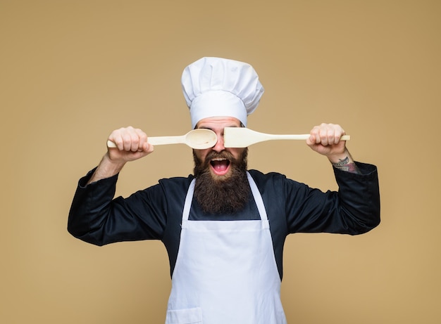 Bearded man preparing to cook food bearded cook with wooden spoon and spatula in hand handsome chef