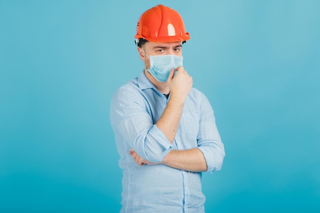 bearded man in a protective orange helmet and mask on a blue background