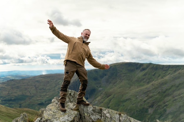 Бородатый мужчина достигает места назначения и на вершине горы на закате в осенний день