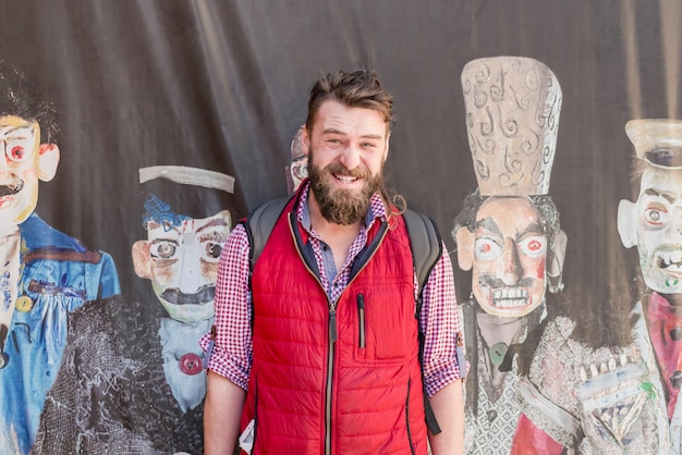 Bearded man in a red vest standing on the background of paintings with Georgian men