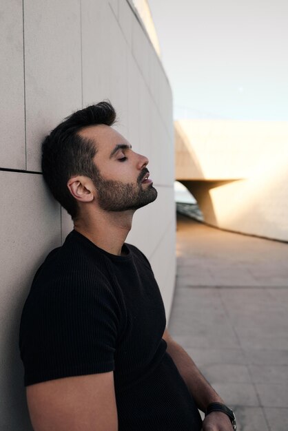 Bearded man resting near wall in street