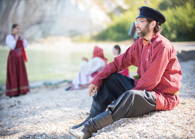 Bearded man in russian national costume sits on the background of an amazing landscape