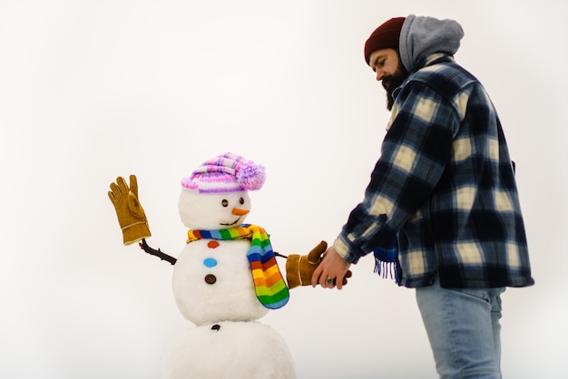 ひげを生やした男が雪だるまと握手する冬の帽子で雪だるまとサンタクロースの男冬の男が立っている