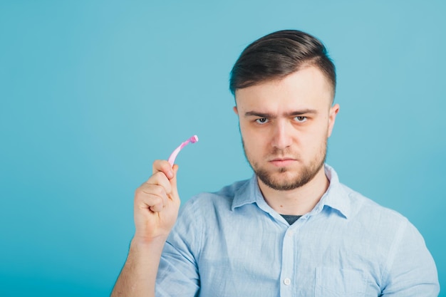 bearded man shaves pink razor on blue background