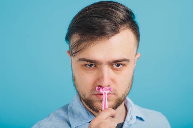 bearded man shaves pink razor on blue background