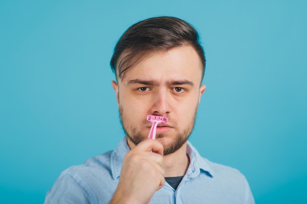 bearded man shaves pink razor on blue background