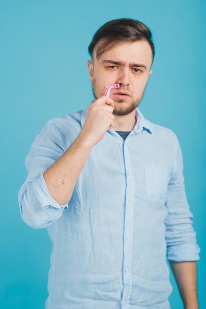 bearded man shaves pink razor on blue background