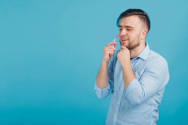 bearded man shaves pink razor on blue background