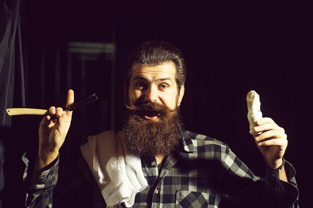 Bearded man shaves with razor