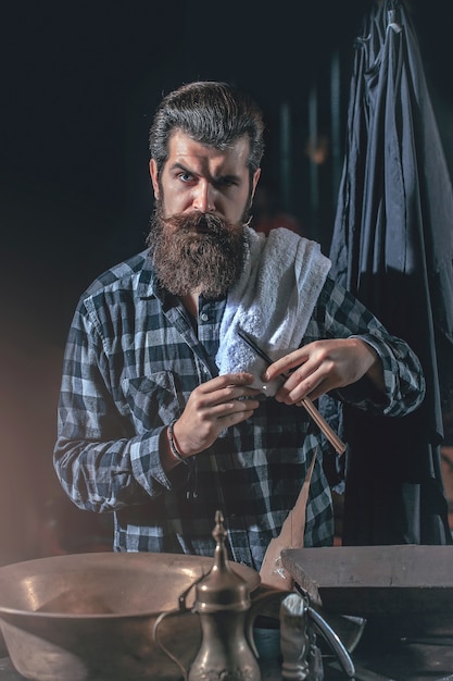 Bearded man shaves with razor