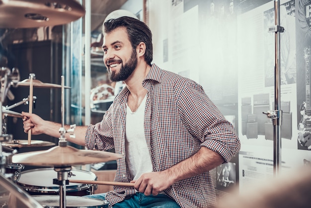 L'uomo barbuto in camicia gioca sul set di batteria.