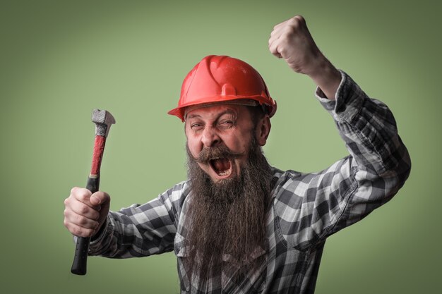 Bearded man shouting and holding a hammer in his hands