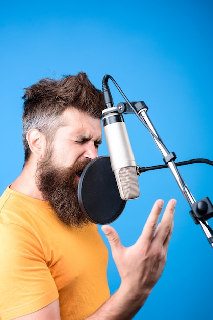 Bearded man singing into microphone music show business\
recording studio male singer with microphone