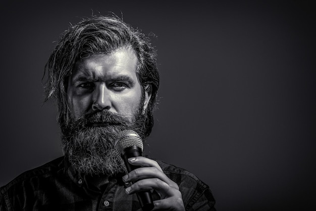 Bearded man singing with microphone Male singing with a microphones Man with a beard holding a microphone and singing Black and white