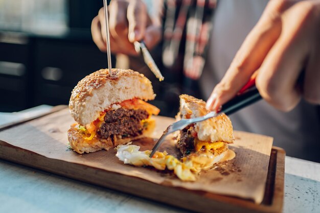 レストランに座って、新鮮なおいしいハンバーガーを食べるひげを生やした男