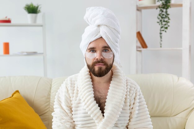 Bearded man sitting with eye patches on his face wrinkles and face home care for men