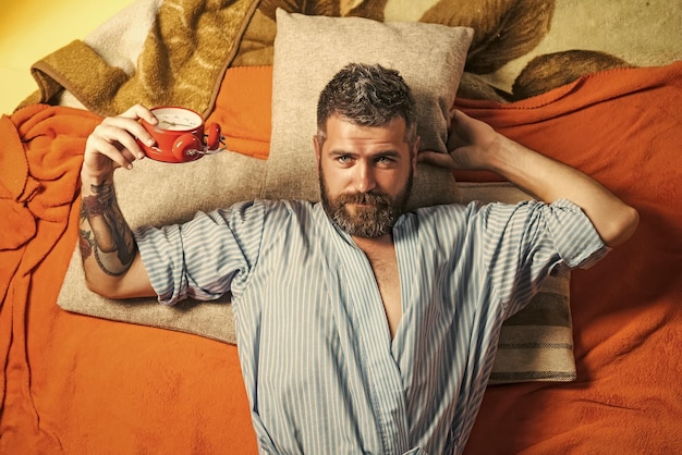 Bearded man sleep on floor with alarm clock.