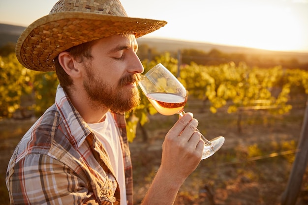 Bearded man smelling wine on vineyard