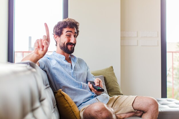 Uomo barbuto che sorride con orgoglio e sicurezza mentre posa trionfante il numero uno, sentendosi come un leader