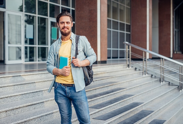 大学の外の階段で笑っているひげを生やした男