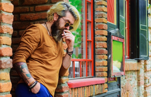 Uomo barbuto che fuma sigaretta cattive abitudini salute sicurezza dipendenza elegante hipster con sigaretta