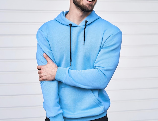 로고가 없는 옅은 파란색 후디 Azure 스웨트셔츠를 입고 서 있는 수염 난 남자 기본 의류 브랜드의 디자인 모형 의류의 로고 복사 공간