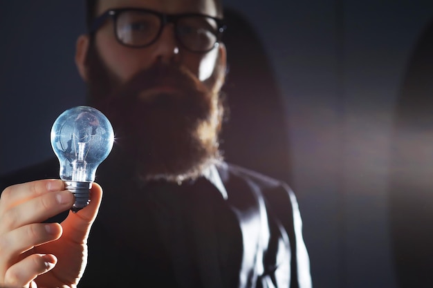 Photo a bearded man in a suit holds an object in his hand concept of time and ideas aspiration and development