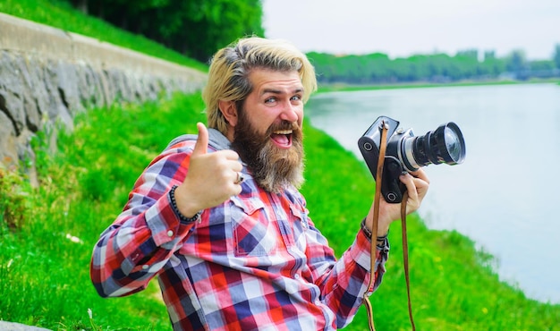 川の趣味でカメラで写真を撮るひげを生やした男とプロのデジタルで笑顔の男を旅行