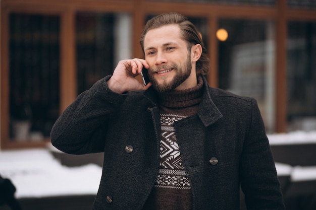 Bearded man talking on the phone in the street in winter