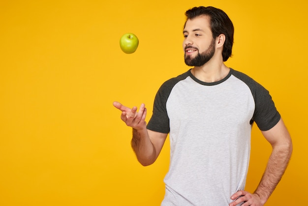 Bearded man tosses up green apple into air.