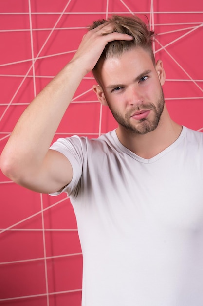 Foto l'uomo barbuto tocca i capelli e il taglio di capelli alla moda. macho con la barba sul viso non rasato. ragazzo con un viso giovane e sano. cura dei capelli in salone o barbiere. bellezza e giovinezza maschile.