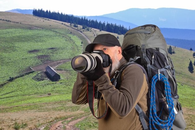 бородатый мужчина туристический фотограф с рюкзаком фотографирует красоту природы