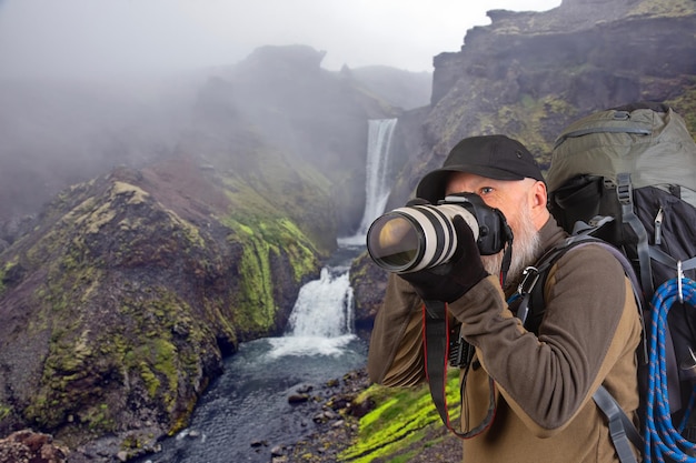 бородатый мужчина туристический фотограф с рюкзаком фотографирует красоту природы