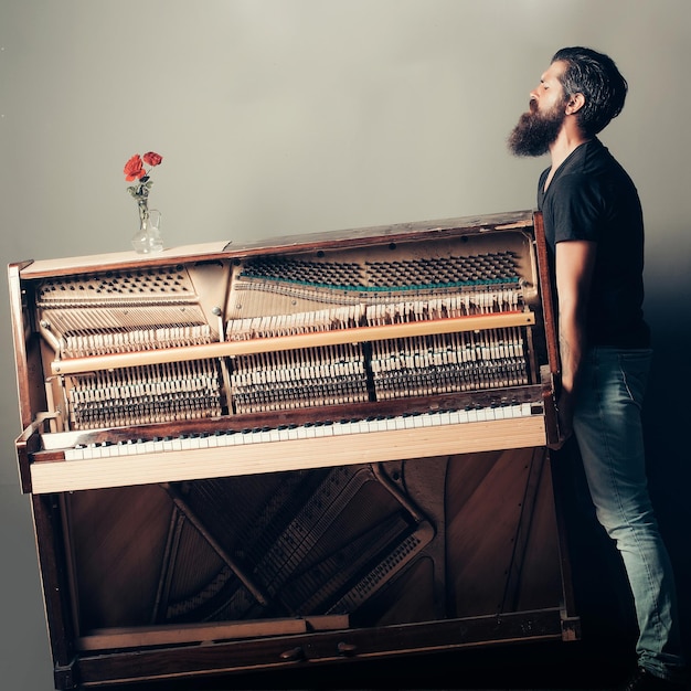 Bearded man trying to move wooden piano with rose