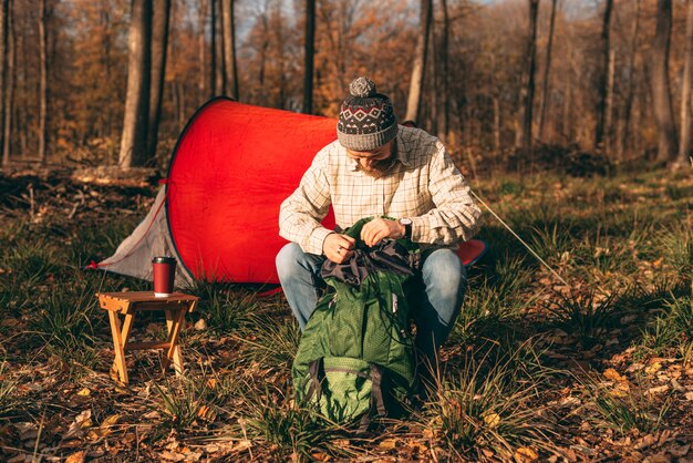 Bearded man unpacking backpack on campsite