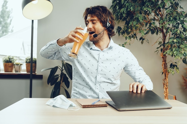 Бородатый мужчина, используя свой ноутбук, выпивая стакан пива