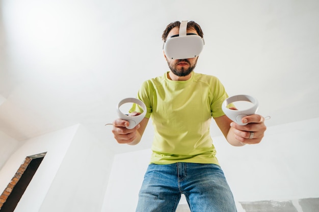 Uomo barbuto che usa occhiali per realtà virtuale prima di iniziare i lavori di ristrutturazione nella sua casa a schiera