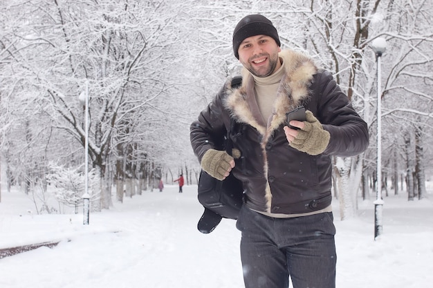 Bearded man walking in a winter park snow season