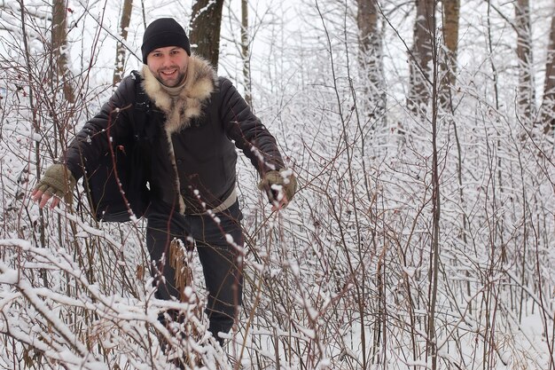 Bearded man walking in a winter park snow season