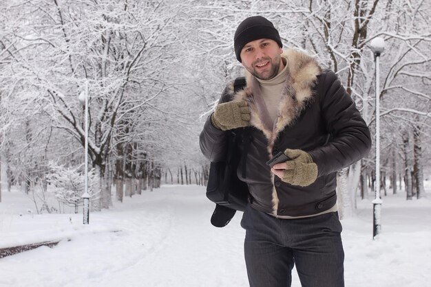 Bearded man walking in a winter park snow season